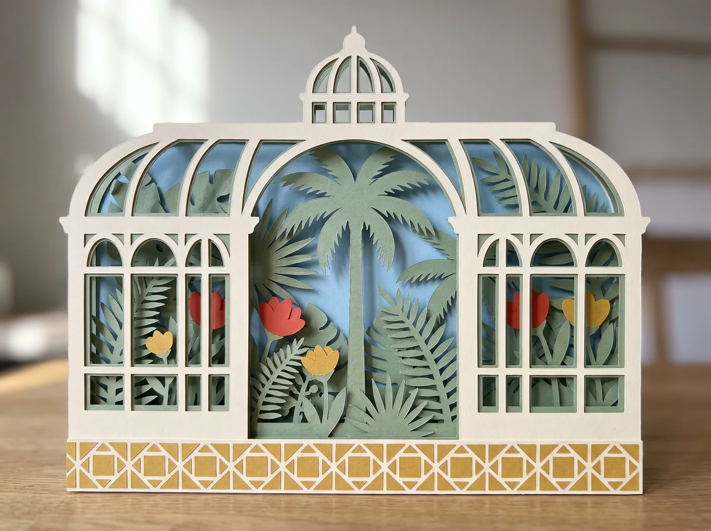 Paper diorama of a glasshouse filled with layered green palm leaves and a few red and yellow flowers.