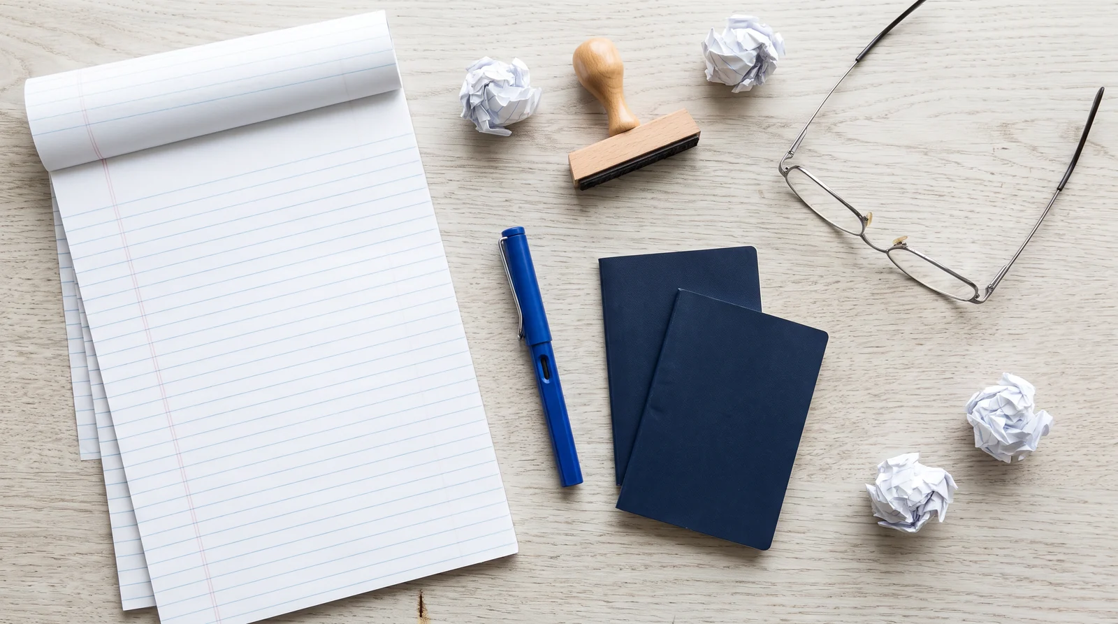 A lawyer's desk seen from above: a ruled legal pad, a blue fountain pen, two blank passports and a rubber stamp
