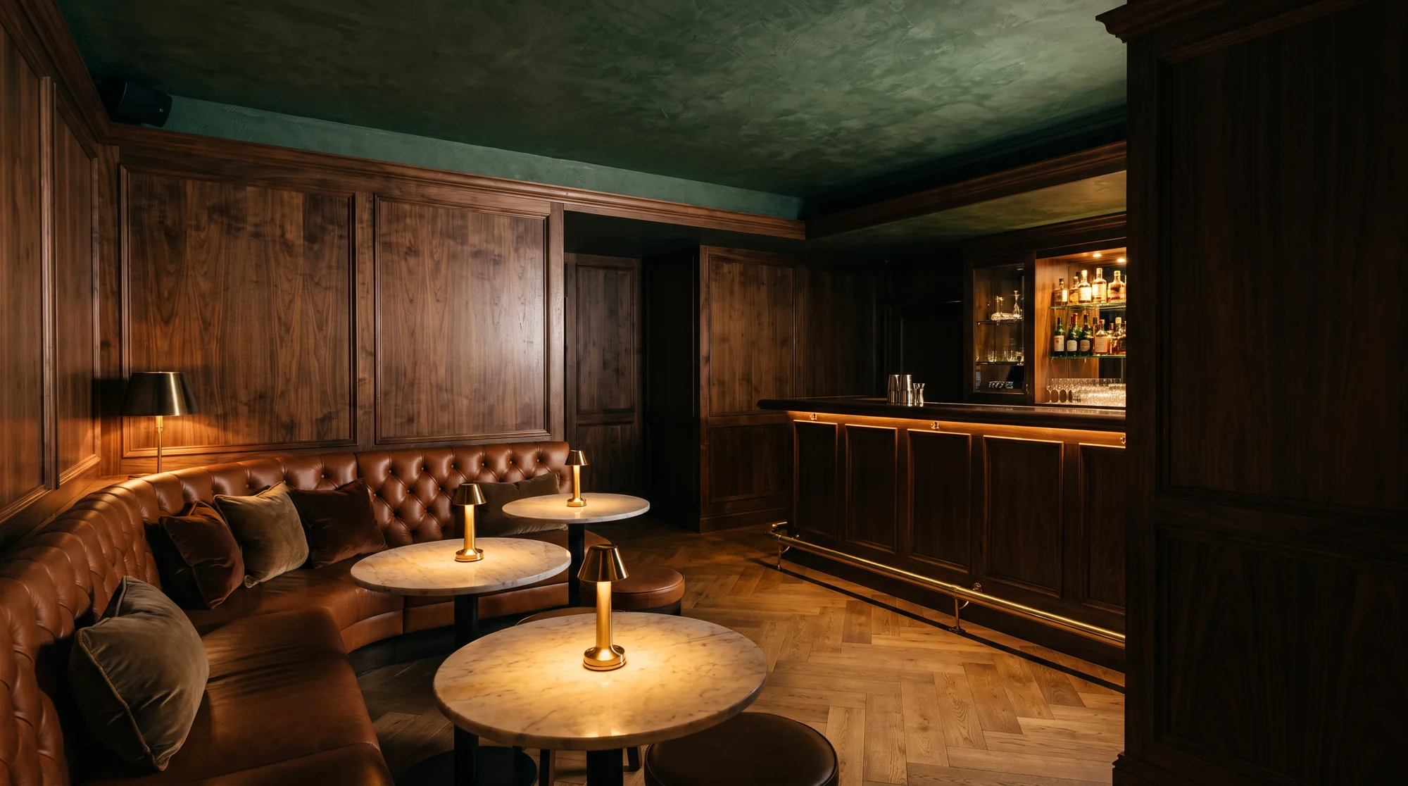 A small hotel bar in walnut and cognac leather lit by brass lamps at dusk