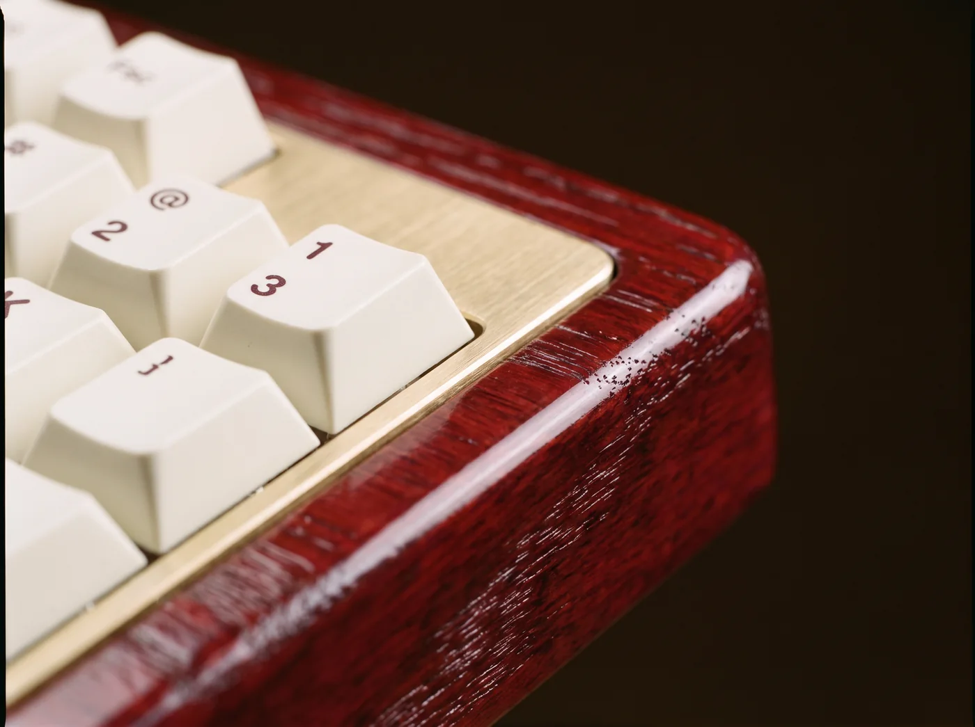 Close view of ivory keycaps beside the brass plate and red lacquered rim