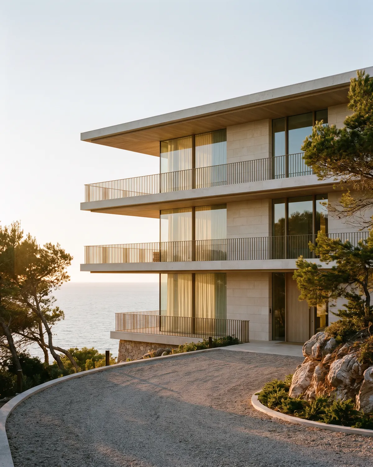 A clifftop villa of three stacked levels of limestone and glass above a calm sea