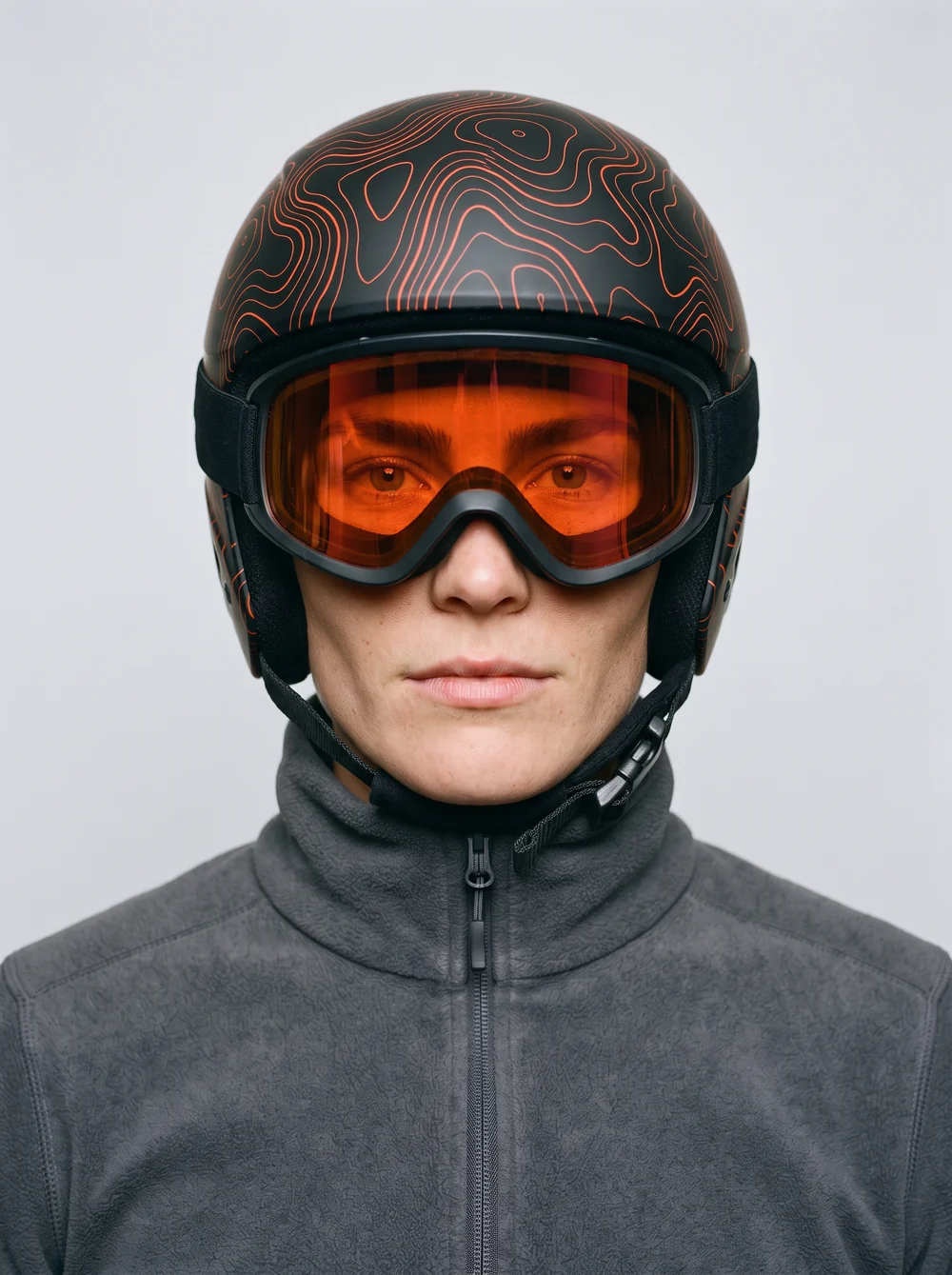 Close-up of Kaia's matte black race helmet with orange contour lines and mirrored goggles