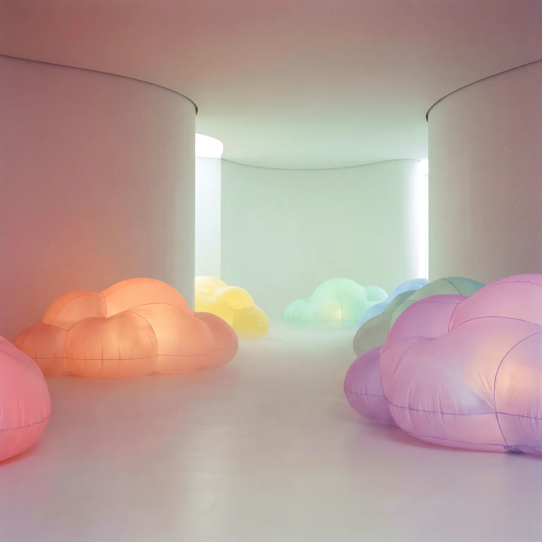 A quiet room of low rounded pastel cloud forms glowing softly from inside
